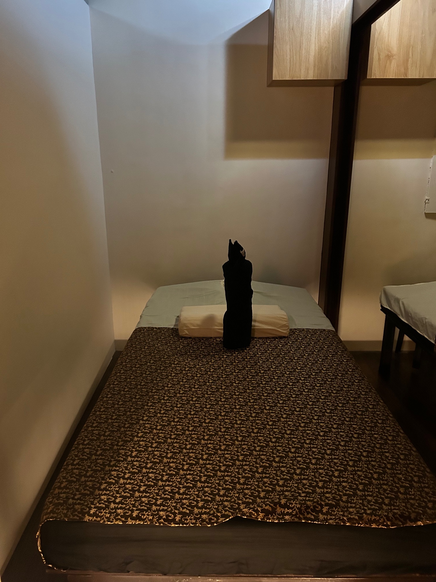 Private Thai massage room with warm lighting and traditional silk bedding